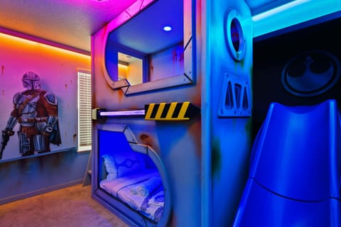 Galactic-themed kids’ room with slide, bunks, glowing lights, and wall art.