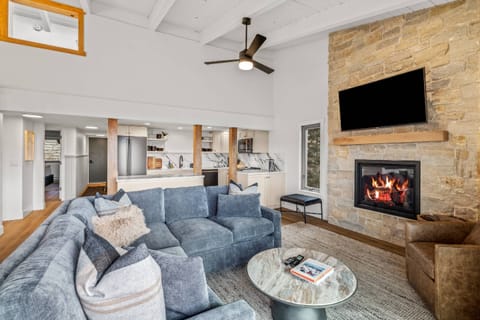 Spacious, modern living room featuring a stone fireplace, open kitchen, and plush sectional