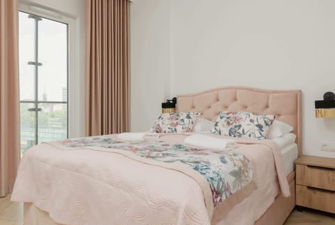 A cozy bedroom with a double bed, soft pink bedding, and matching curtains, creating a warm and inviting atmosphere.
