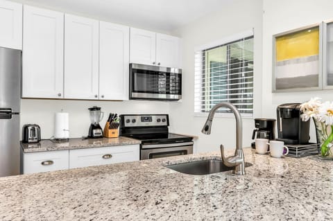 This remarkable open-plan kitchen boasts luxury and impeccable style. Fit with modern white shaker cabinets, and granite counters, stainless steel appliances, a filter coffee brewer, a Keurig, a blender, dinnerware service for 6, and everything you need.