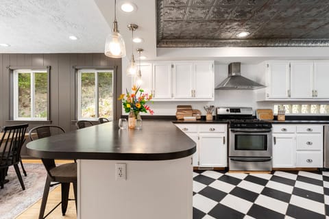 Bright kitchen w/ checkered floors, island seating & statement lighting