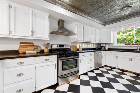 Spacious kitchen w/ stainless range, white cabinetry & bold checkered floors