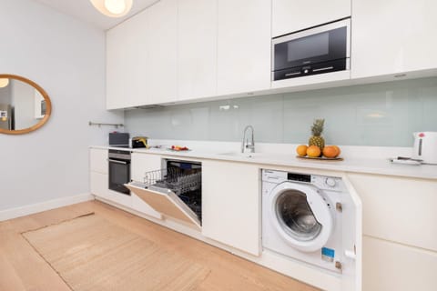 A fully equipped kitchen with a washing machine, microwave, and a clean, practical layout.
