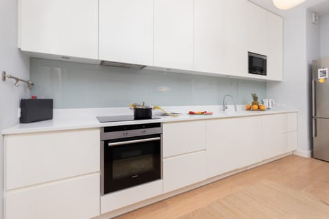 A sleek kitchen with white cabinetry, built-in appliances, and a bright, minimalist design.
