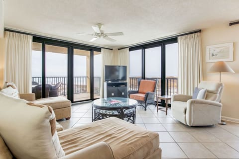 Open-concept living room with floor-to-ceiling Gulf views and L-shaped sleeper sofa at Wind Drift Orange Beach condo