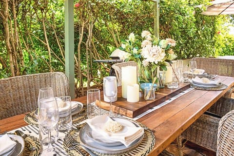Rattan chairs and rustic wood welcome barefoot meals kissed by blossoms and cloaked in gentle hush.   