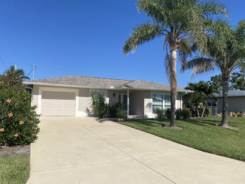 Front of House with beautiful landscaped yard and mature palm trees