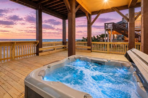 Covered beachfront deck with private hot tub, wooden pergola, and unobstructed ocean views