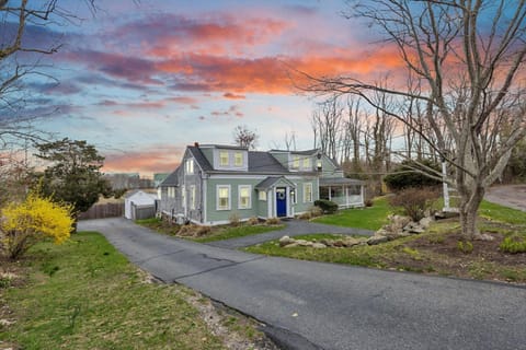 Green exterior with a gravel driveway and lawn — your Cape Cod home for the stay