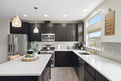 Modern Kitchen - Sleek Dark Cabinets, Bright Countertops & Elegant Lighting