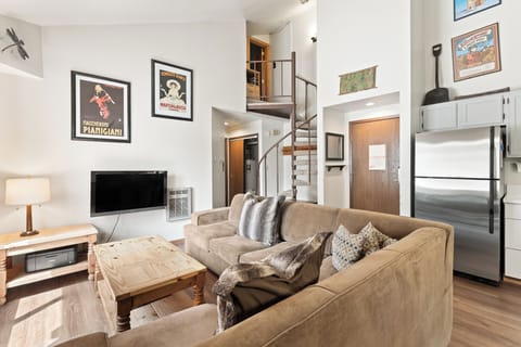 Your cozy retreat features high ceilings, warm wood accents, and a spiral staircase leading to your private loft. Sink into the plush sofa after a day of adventure, while eclectic artwork adds character to this inviting open-concept space.