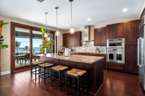 Chef’s kitchen with granite island, bar seating, and stainless appliances.