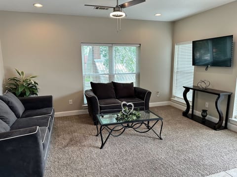 Bright, cozy living room with TV, large windows, and comfy seating