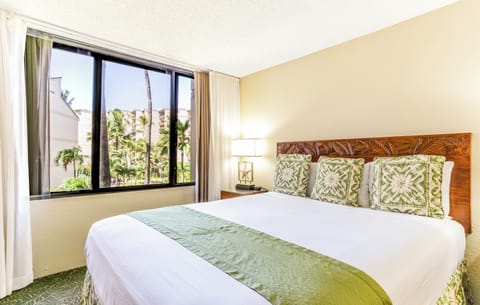 Relax in your bright bedroom with tropical garden views through large windows. The handcrafted wooden headboard and lush green accents bring island elegance to your peaceful retreat.