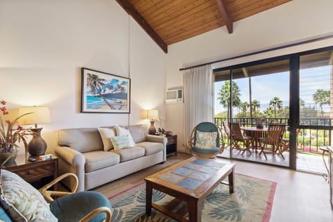 Relax in your sunlit living space with vaulted wood ceilings, coastal-inspired decor, and a private balcony framing palm trees and ocean breezes.