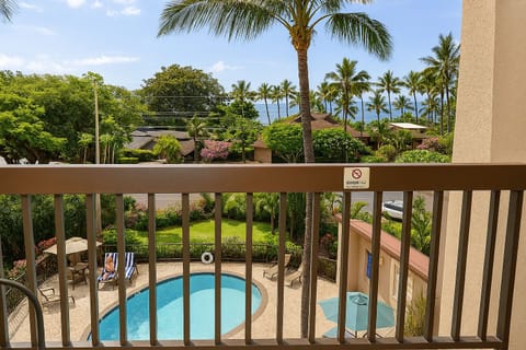 Soak in tropical ocean views from your private balcony, where swaying palms and a sparkling pool below create your perfect Hawaiian getaway.