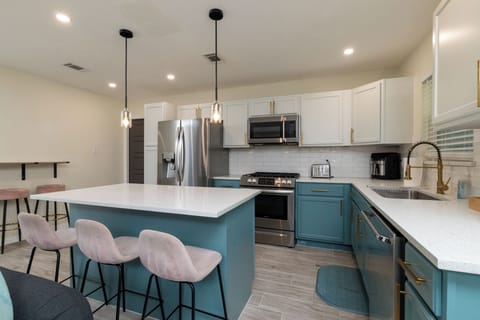 Stylish kitchen island with pink velvet stools and pendant lighting