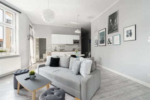 Bright, spacious living room with a comfortable gray sofa, modern decor, and large windows bringing in plenty of natural light.

