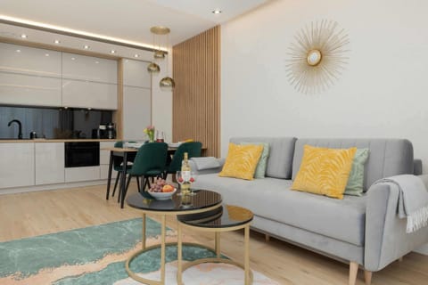 Stylish living room featuring a gray sofa with yellow accent pillows, a modern dining area, and sleek decor.

