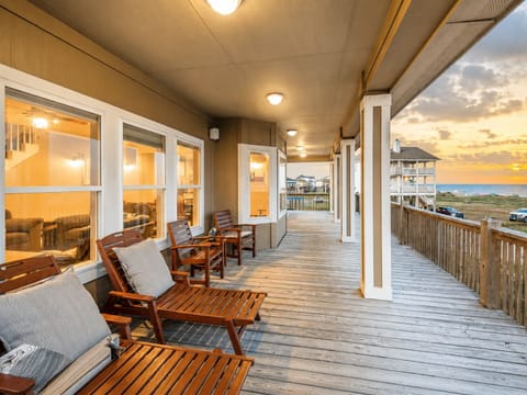 Spacious covered deck with outdoor lounge seating, ceiling fans, warm lighting, and open views—an ideal spot for relaxing after a day at Crystal Beach.