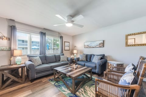 Relax in your spacious living room featuring plush sofas, coastal decor, and natural light streaming through windows.