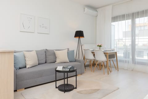 Bright and cozy living room with a gray sofa, minimalist decor, and a coffee table for relaxing.


