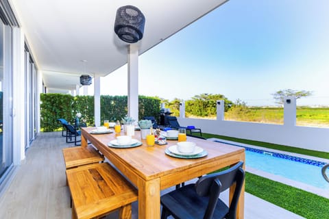 Step into your private covered terrace where sunny breakfasts meet poolside ease. Dine al fresco under modern pendants while vibrant greenery and open horizons frame your mornings.
