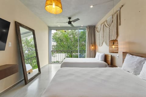 Bright room with cozy beds, smart TV, and tropical balcony views.