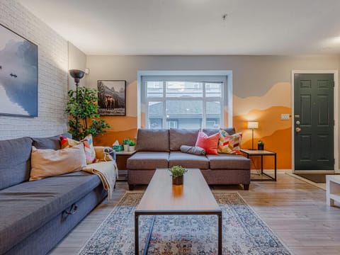 The living room offers plenty of comfortable seating, perfect for relaxing after a day of exploring. Bright accents and cozy textures create a warm, inviting space to unwind or gather with friends.