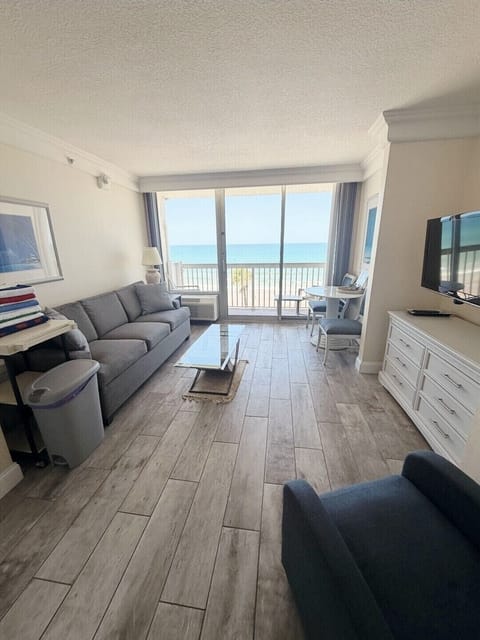 Bright oceanfront living room with balcony views and cozy seating