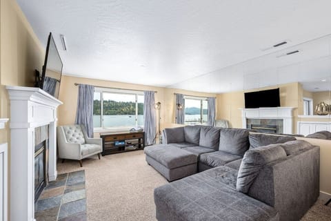 Unwind in this spacious living room featuring a plush sectional sofa, cozy fireplace, and stunning lake views through large windows.