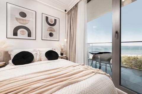 Modern bedroom with large windows, neutral color palette, and stylish wall art.

