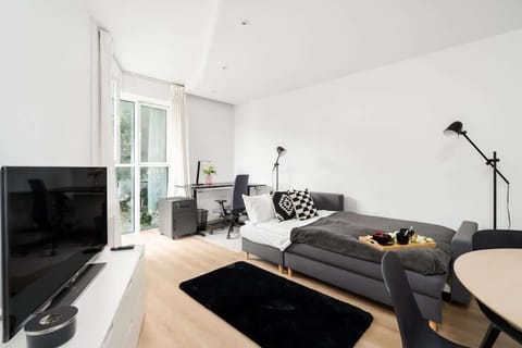 Living room corner with a comfortable black sofa, stylish décor, and plenty of light.

