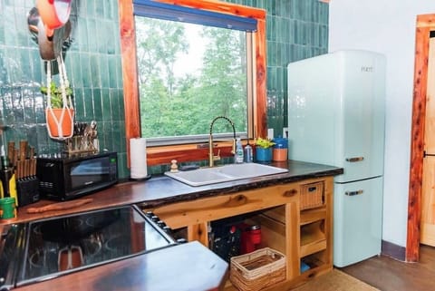Kitchen with apartment-size fridge, stove, and microwave. Dishes and small appliances are inside cabinets