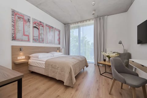 Modern bedroom with a comfortable bed, minimalist decor, and a large window allowing natural light.

