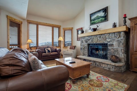 Unwind by your stone fireplace with leather seating and mountain views through expansive windows—your perfect alpine retreat awaits.