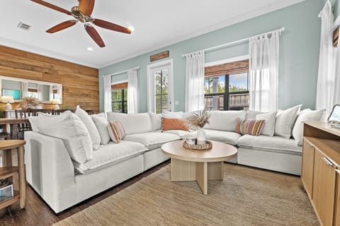 Bright and airy living room with a cozy white sectional, wood accent wall, and natural textures—perfect for relaxing after a day on the beach.