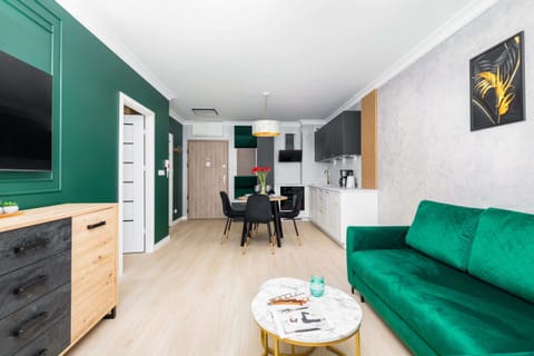 Wide view of the open living and dining area, showcasing the green sofa and modern furnishings.