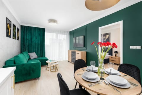 Bright and modern living area with a green sofa, dining table, and decorative accents in a stylish design.
