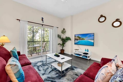 Bright living room with red sofas and balcony access overlooking trees