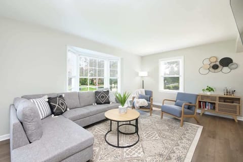 - Bright living room with large sectional sofa and patterned pillows   - Modern seating with accent chairs and coffee table centerpiece   - Natural light through wide windows creates a cozy relaxing space  