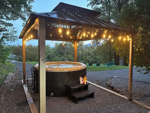 Covered hot tub with privacy screening and warm string lights for relaxing year-round