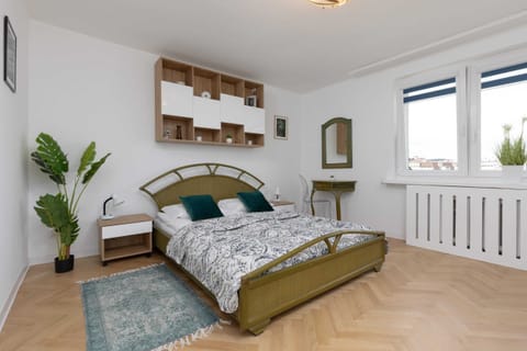 A cozy bedroom with a large bed, green and gold accents, and wooden furniture for a warm ambiance.


