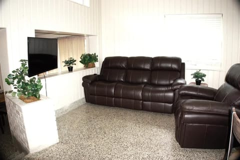 Living Room 1 with leather couch & recliner facing a wall mounted tv.