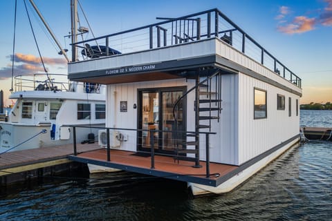 Modern Charm docked at Lighthouse Point Marina in Canton at sunset, with the spiral staircase leading to the rooftop and warm interior lights glowing from within.