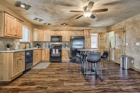 Full kitchen with warm wood cabinets, black appliances, and a central island with bar seating. Plenty of counter space and open floor area make it easy to cook, prep meals, and keep the conversation going nearby.