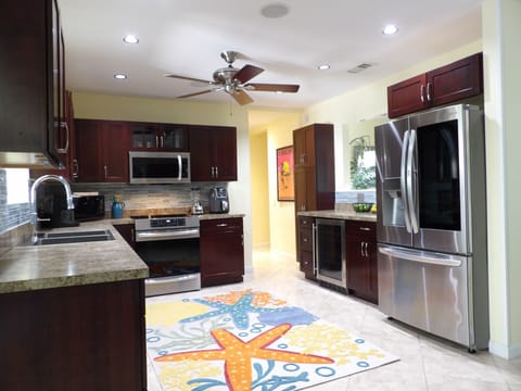 Stainless kitchen opens to dining area, induction stove, airfryer, 2 microwaves.