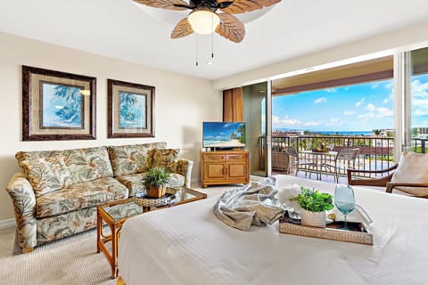 Your tropical bedroom suite features crisp white linens and vibrant blue accents, with floor-to-ceiling windows framing stunning ocean views.