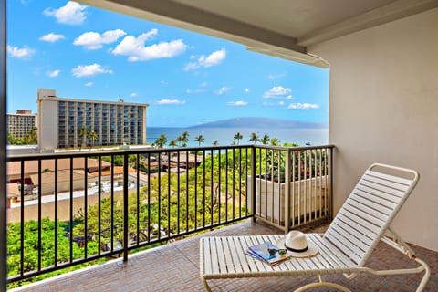 Furnished lanai with lounge seating and railing detail, offering elevated views of lush grounds and Maui’s turquoise shoreline.