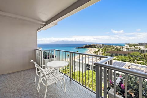 Stunning coastal views stretch across turquoise waters and sandy shores from this private balcony, where island mountains meet endless ocean horizons.